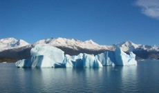 Blue glacial iceberg floating along the coast